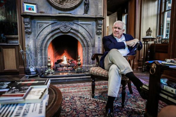 Harlan Crow sits in front of a fireplace