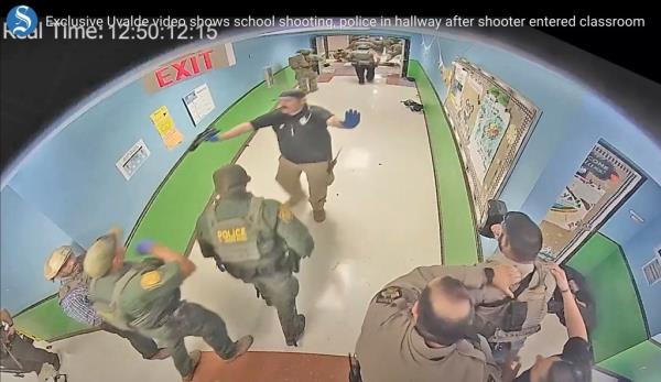 Uvalde police are pictured waiting in the hallway at Robb Elementary School as the shooting was taking place on May 24, 2022.